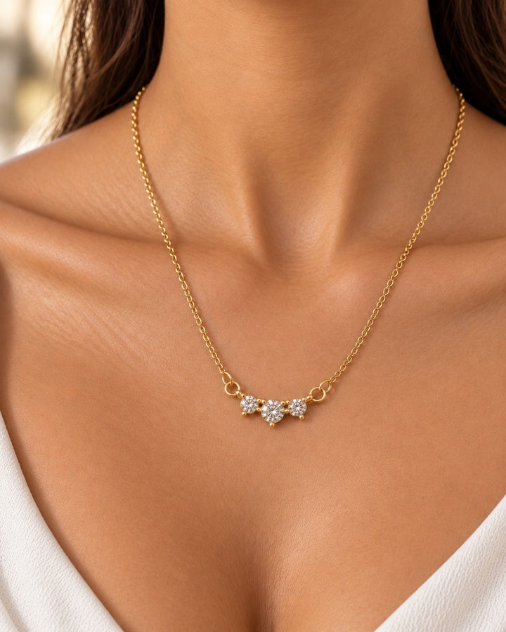 Elli Jewellery gold plated necklace featuring a triple cubic zirconia trilogy pendant worn on a model