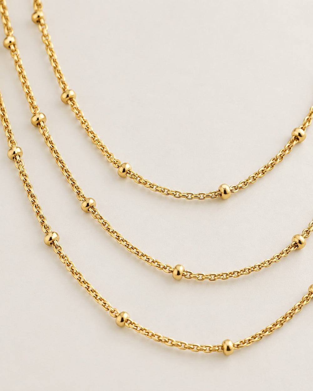 Elli Jewellery gold plated triple layered chain necklace with delicate bead accents on a neutral background