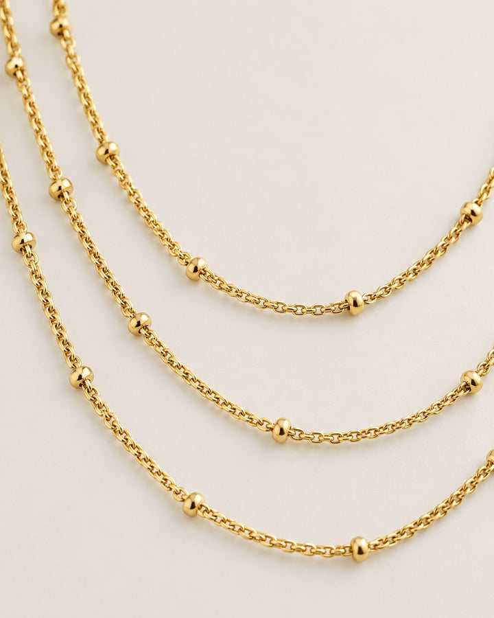 Elli Jewellery gold plated triple layered chain necklace with delicate bead accents on a neutral background