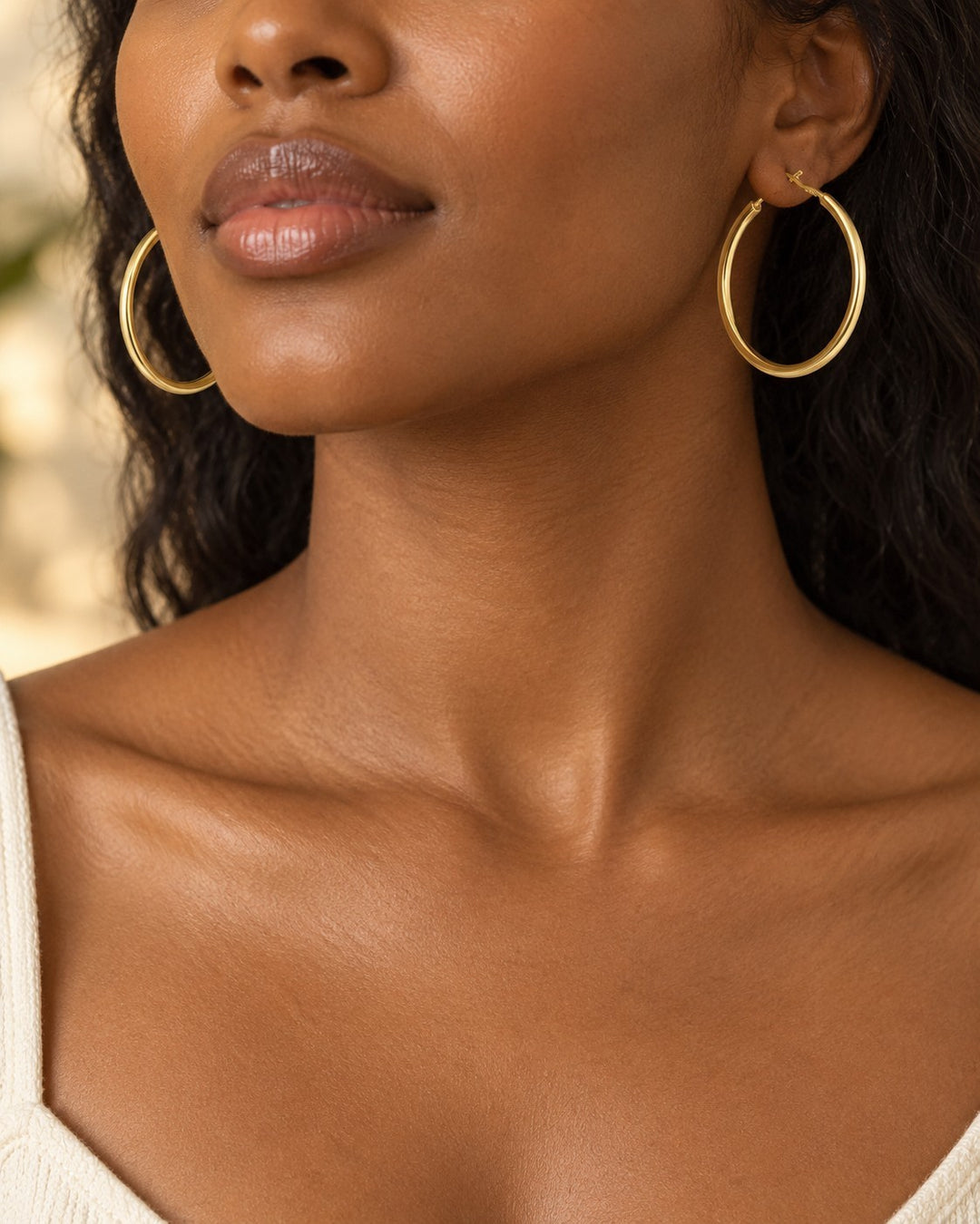 Model wearing Elli Jewellery 18ct gold plated brass tube hoop earrings with a smooth, polished finish.