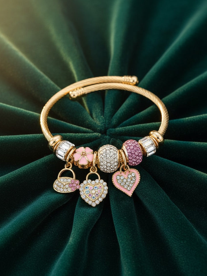 Elli Jewellery gold plated twisted cuff bracelet featuring pink enamel and crystal heart charms on green velvet.