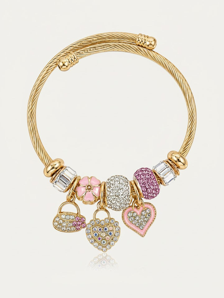 Elli Jewellery gold plated twisted cuff bracelet with dangling heart charms, pink enamel, and crystal accents.