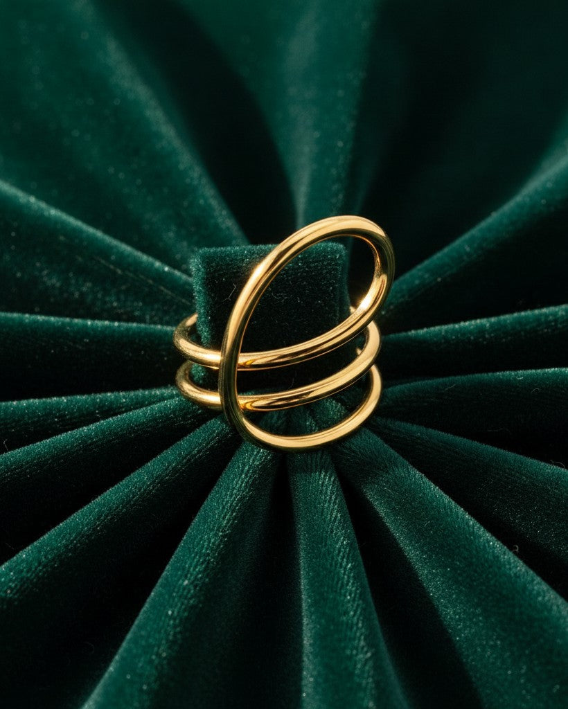 Elli Jewellery gold-toned twisted dome statement ring with a chunky sculptural design on a dark green velvet background.