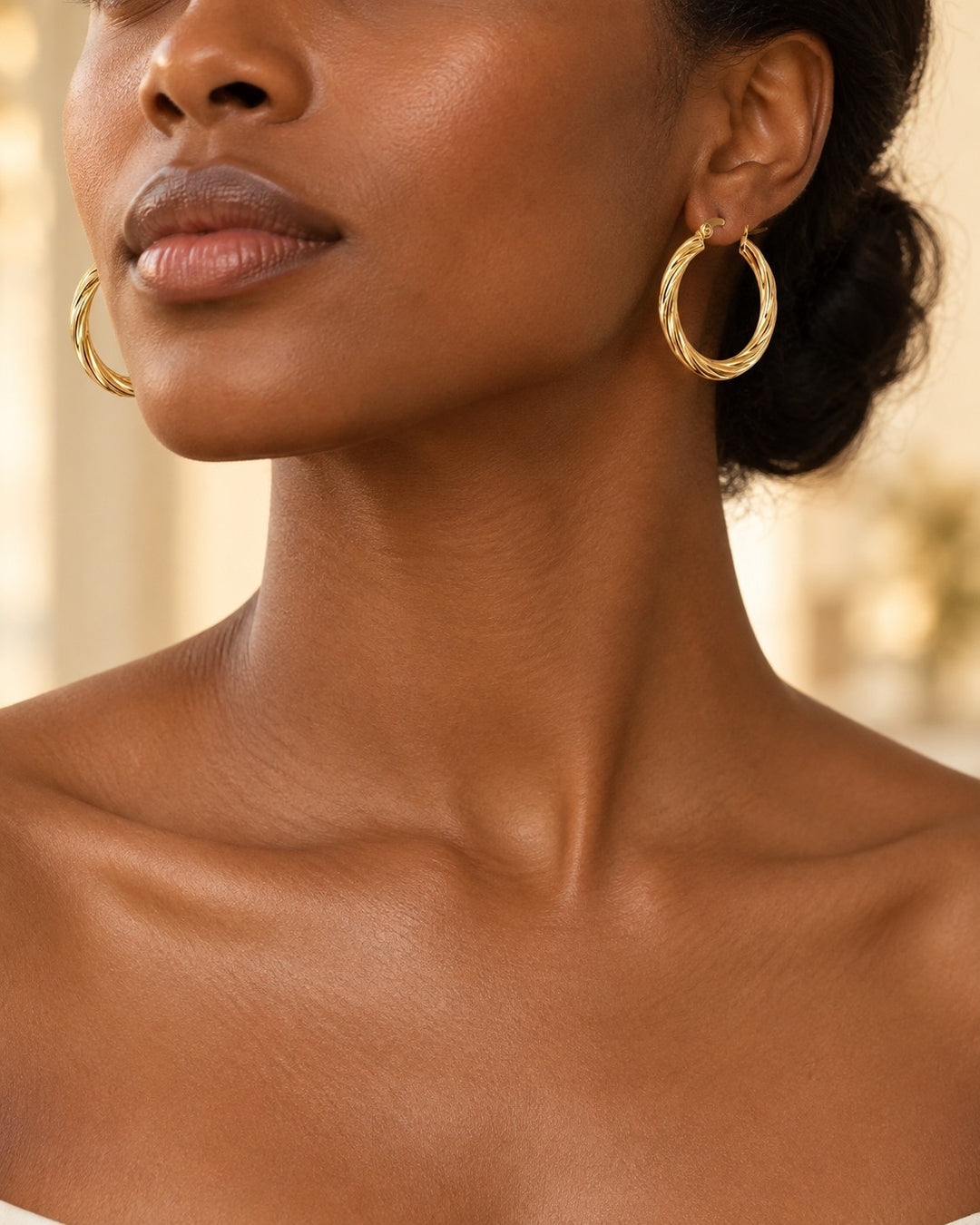 Elli Jewellery gold-toned large hoop earrings with a twisted texture worn by a model with an elegant updo.