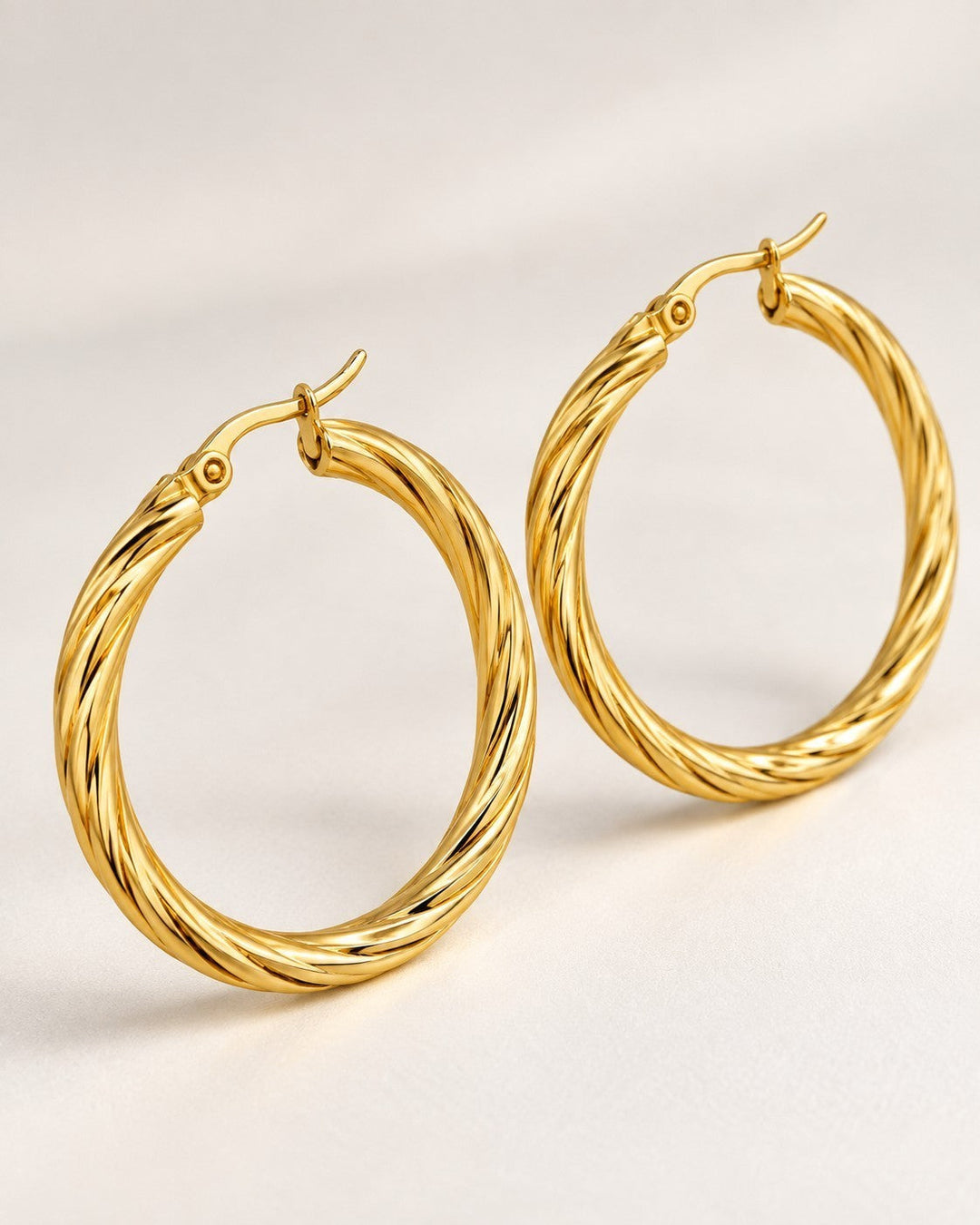 Elli Jewellery large gold-toned hoop earrings with a twisted texture design on a neutral background.