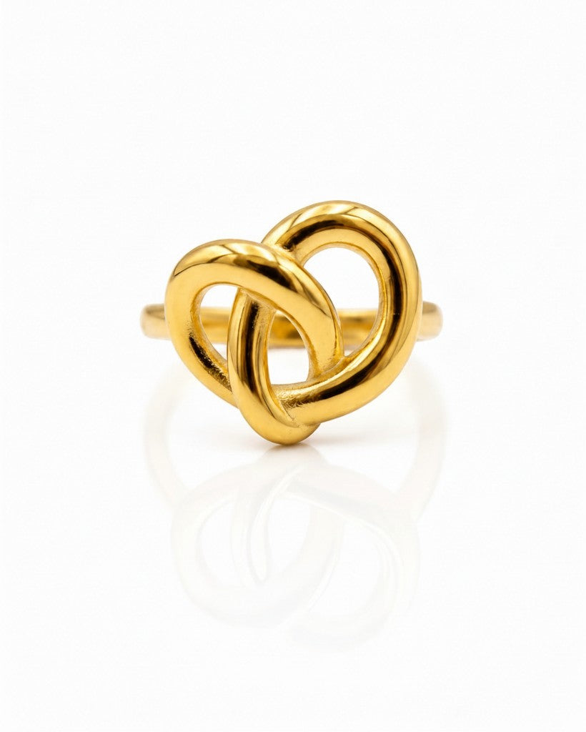 Elli Jewellery gold plated statement ring featuring a sculptural twisted knot design on a reflective white surface.