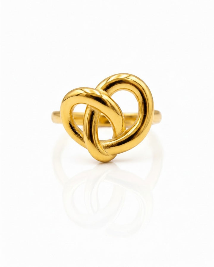 Elli Jewellery gold plated statement ring featuring a sculptural twisted knot design on a reflective white surface.