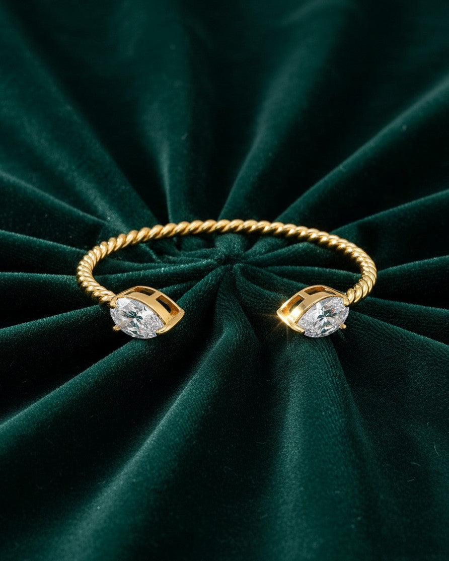 Elli Jewellery gold plated twisted rope cuff bracelet with marquise cut stones on a dark green velvet background