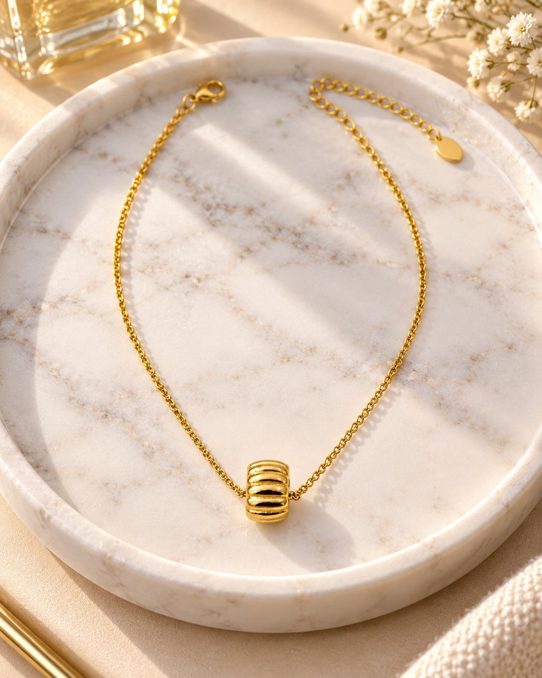 Elli Jewellery gold plated necklace featuring a sculptural oval tyre link pendant on a delicate chain on a marble tray