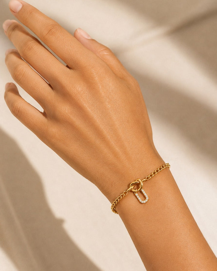 Elli Jewellery gold plated chain bracelet featuring a diamante U initial charm worn on a woman's wrist