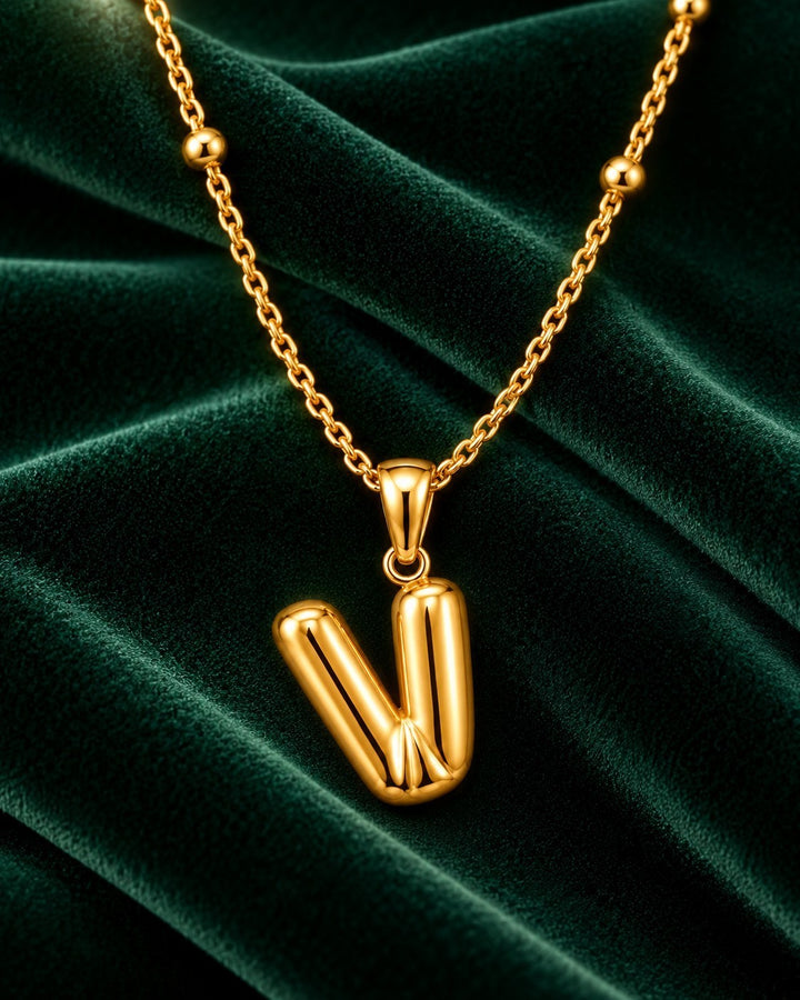 Elli Jewellery gold plated chunky V pendant necklace on a dark green velvet background