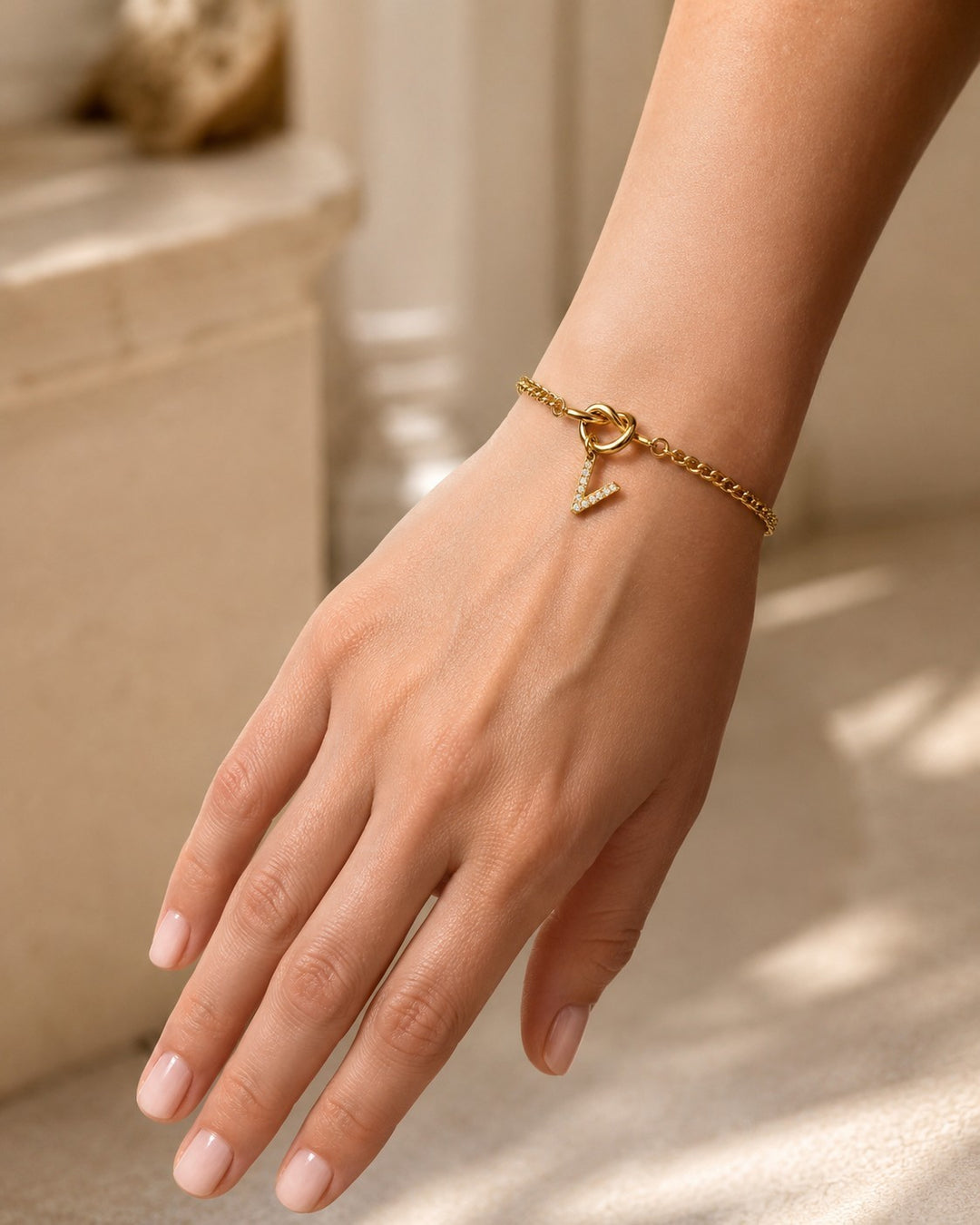 Elli Jewellery gold plated V-shape diamante bracelet with clear crystals on a delicate chain worn on a woman's wrist.