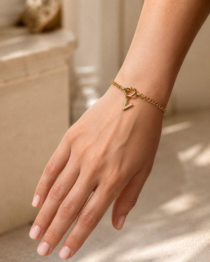 Elli Jewellery gold plated V-shape diamante bracelet with clear crystals on a delicate chain worn on a woman's wrist.