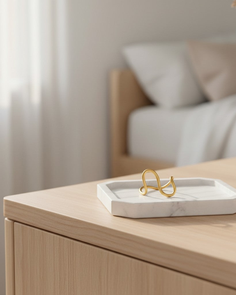 Elli Jewellery gold plated curved wave band ring resting on a white marble tray in a minimalist bedroom setting.