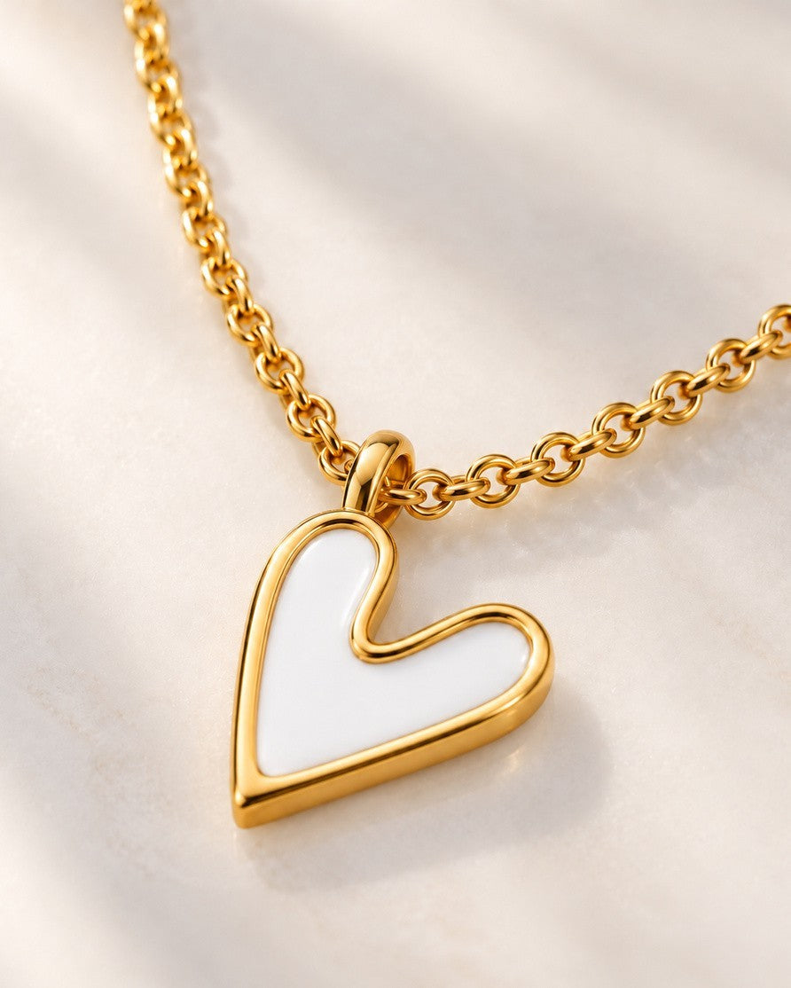Elli Jewellery gold plated heart pendant necklace with white enamel inlay on a delicate chain against a marble surface