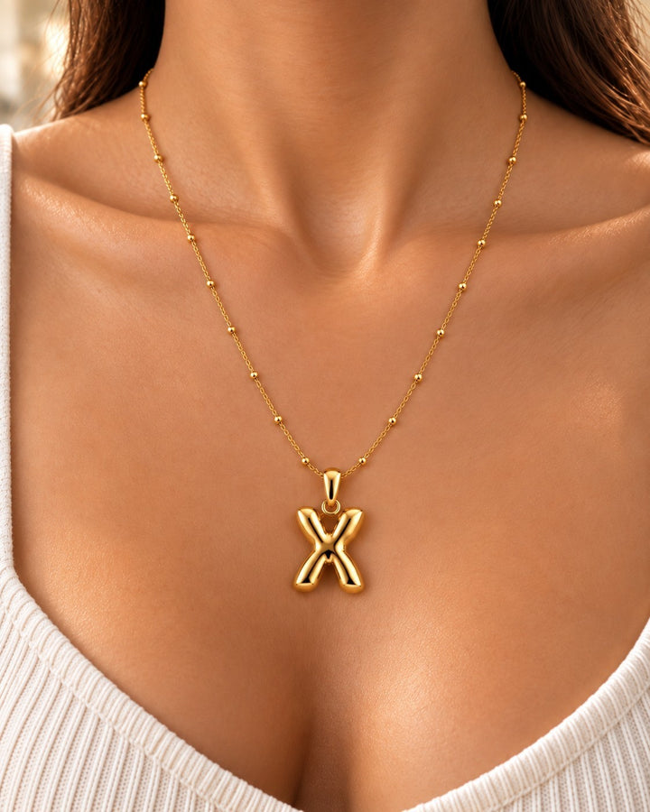 Elli Jewellery gold plated waterproof necklace featuring a chunky X-shaped pendant on a delicate beaded chain.