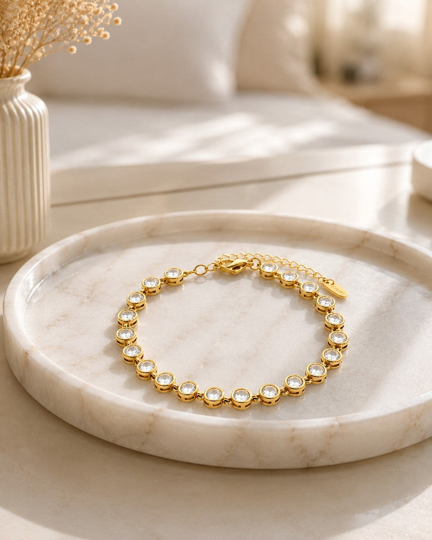 Elli Jewellery gold plated tennis bracelet featuring round-cut clear zirconia stones on a marble display tray