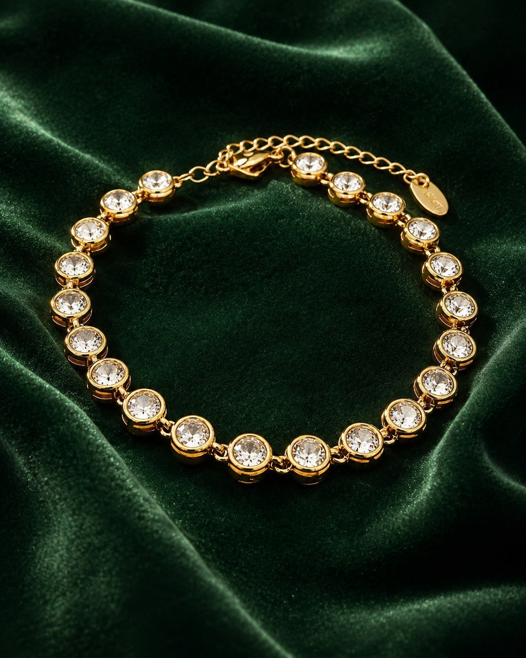 Elli Jewellery gold plated tennis bracelet featuring round-cut clear zirconia stones on a dark green velvet background