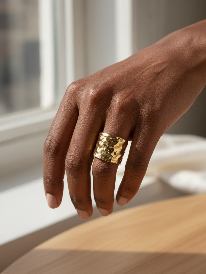 Elli Jewellery wide hammered gold plated ring worn on a finger, featuring a textured dimpled surface.