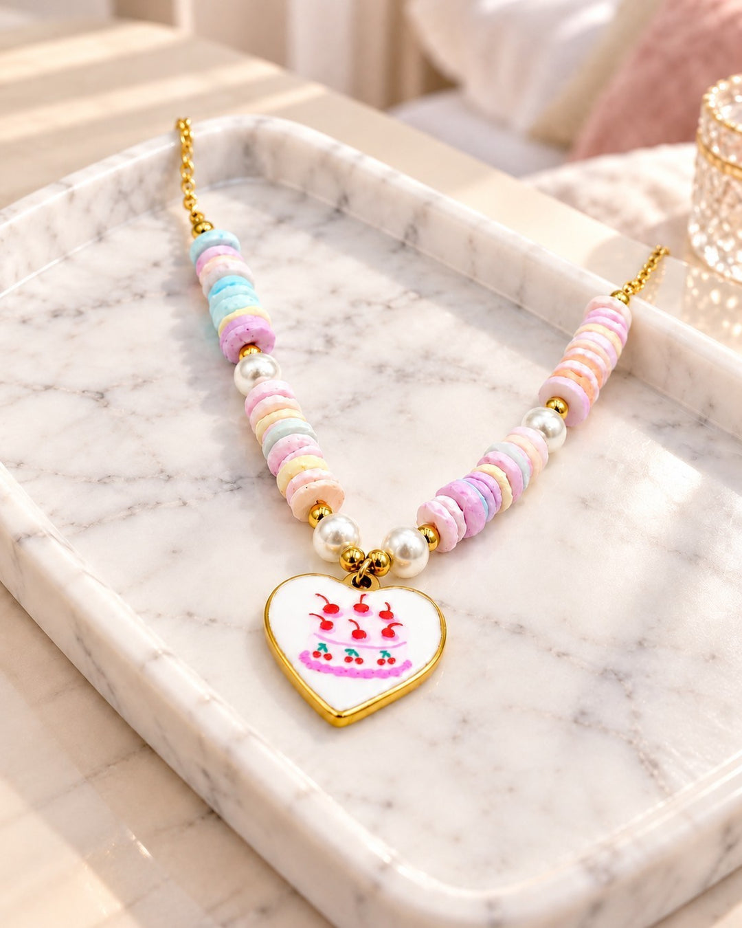 Elli Jewellery gold plated necklace featuring pastel disc beads, faux pearls, and a heart charm with a cake design.