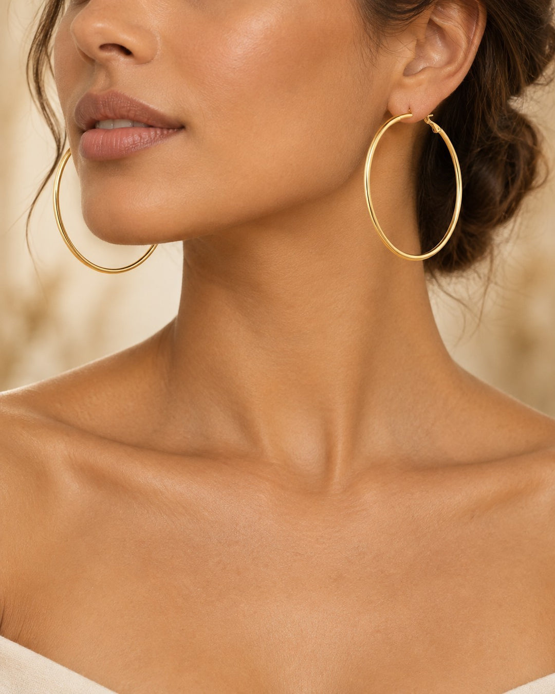 Elli Jewellery large smooth 18ct gold plated hoop earrings worn by a woman with an elegant updo