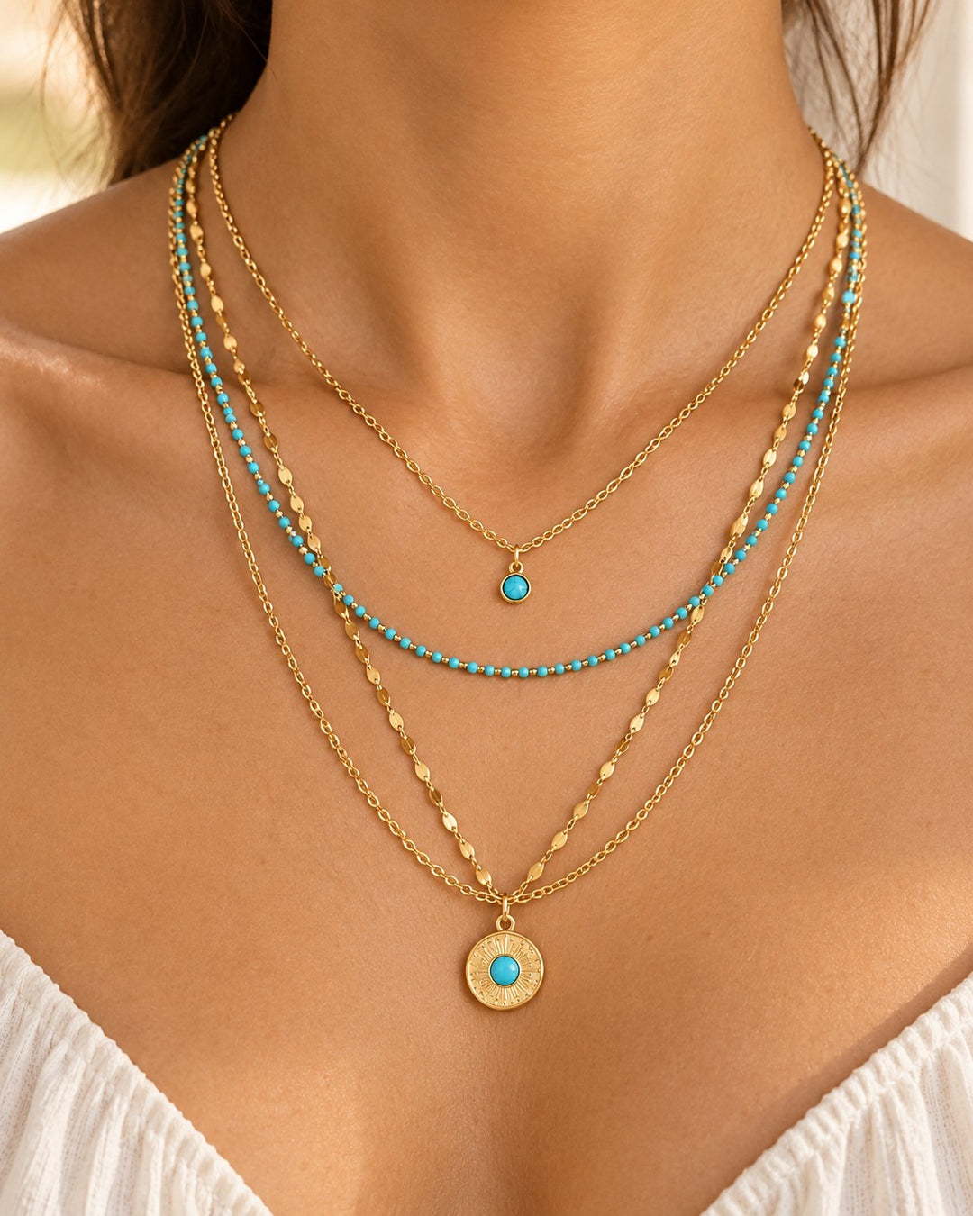 Elli Jewellery layered gold necklace set featuring delicate chains, turquoise beads, and a sunburst pendant.
