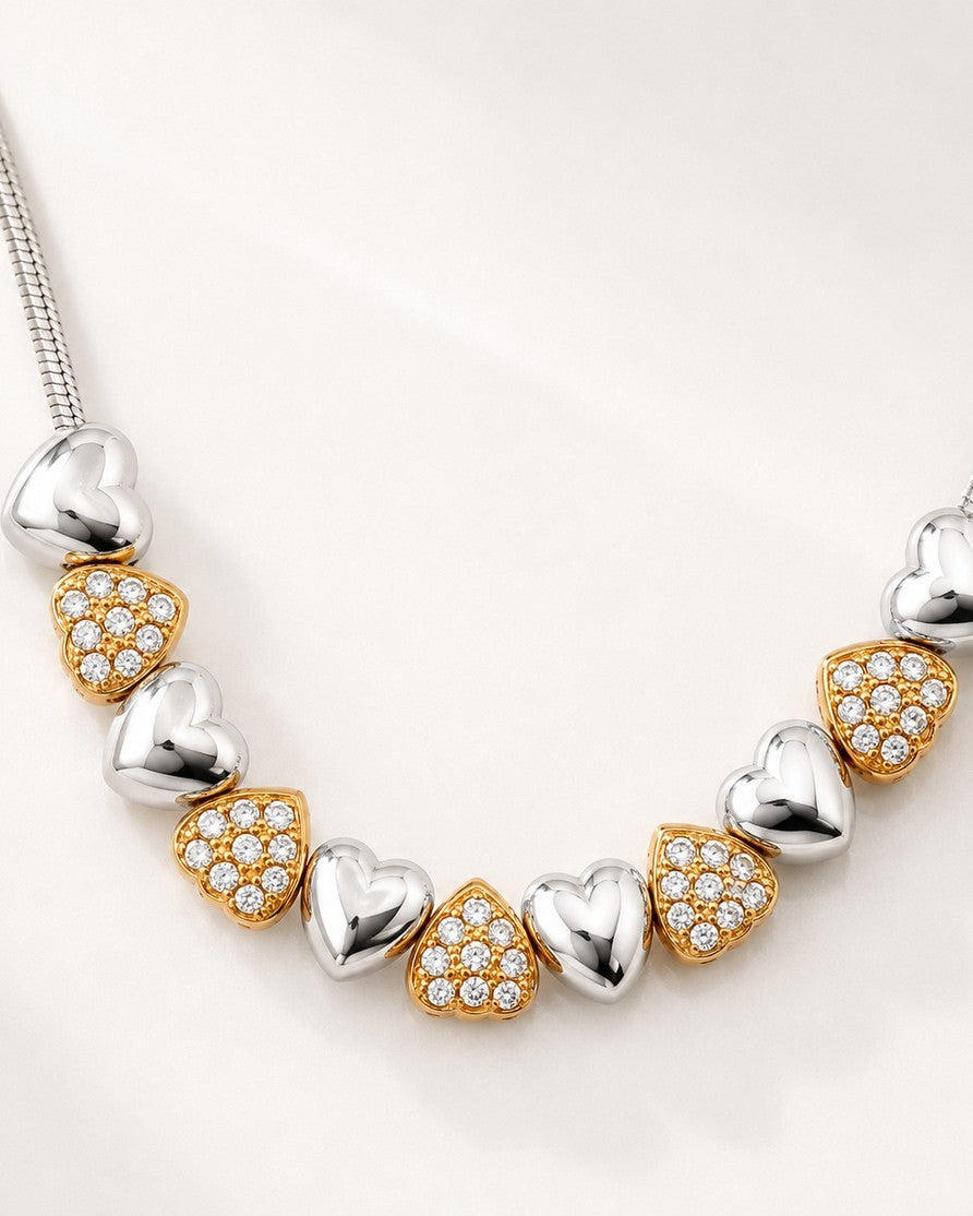 Elli Jewellery two-tone necklace featuring alternating rhodium-plated silver and crystal-set gold-plated heart charms.