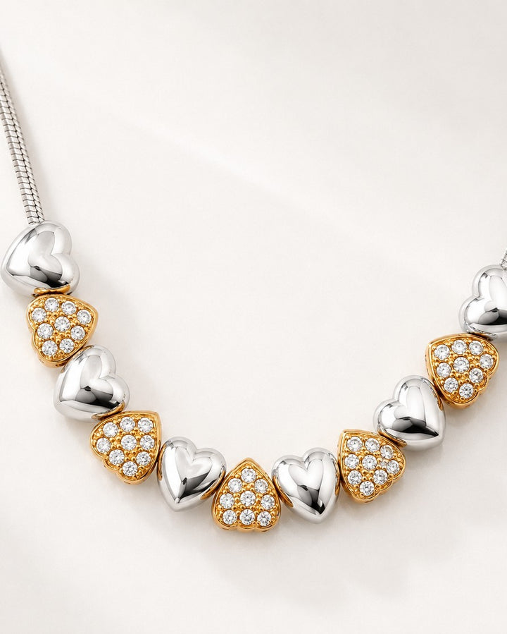 Elli Jewellery two-tone necklace featuring alternating rhodium-plated silver and crystal-set gold-plated heart charms.