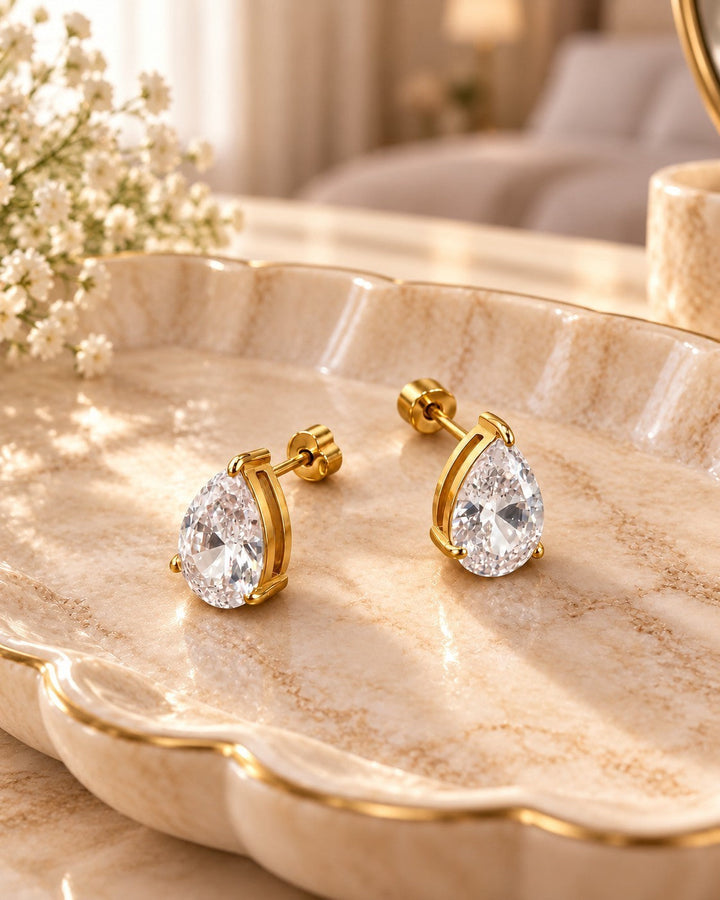 Elli Jewellery pear shaped cubic zirconia stud earrings with a gold plated finish resting on a decorative tray.