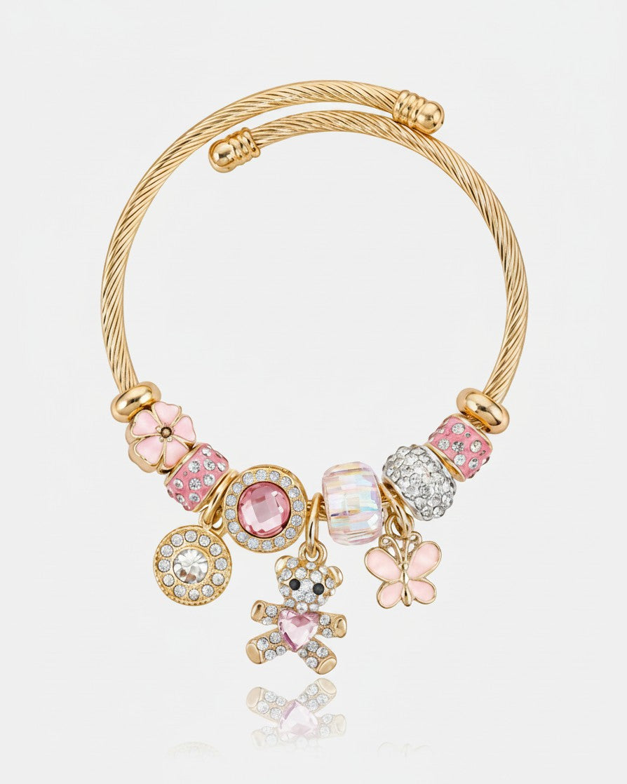 Elli Jewellery gold plated cuff bracelet featuring pink crystals, charms of a teddy bear and flower on a twisted band.
