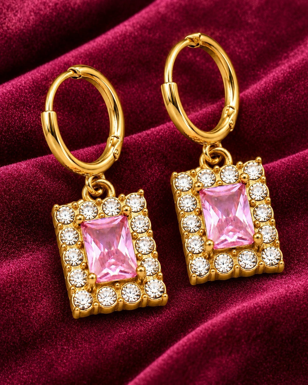Elli Jewellery gold plated huggie hoop earrings featuring rectangular pink cubic zirconia stones on velvet fabric.