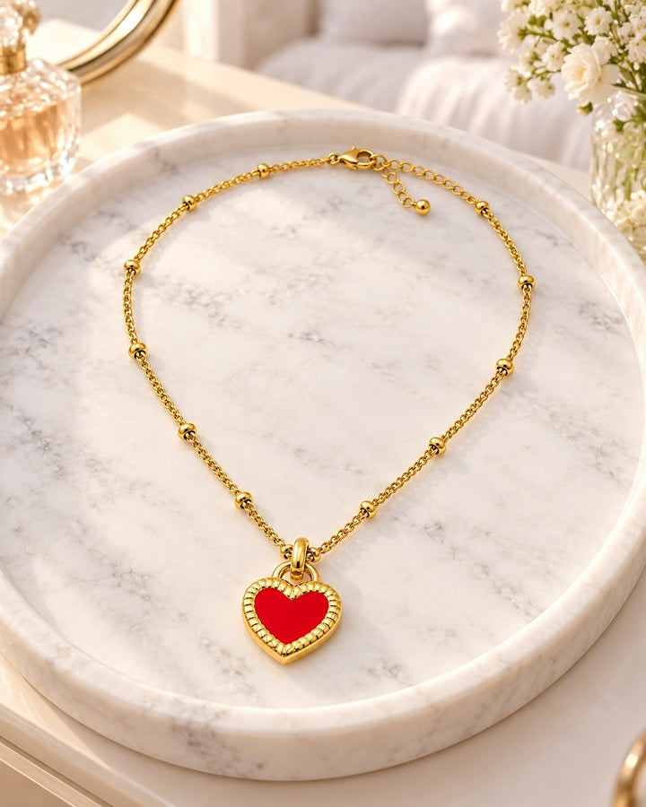Elli Jewellery gold plated necklace featuring a vibrant red enamel heart pendant on a delicate beaded chain.