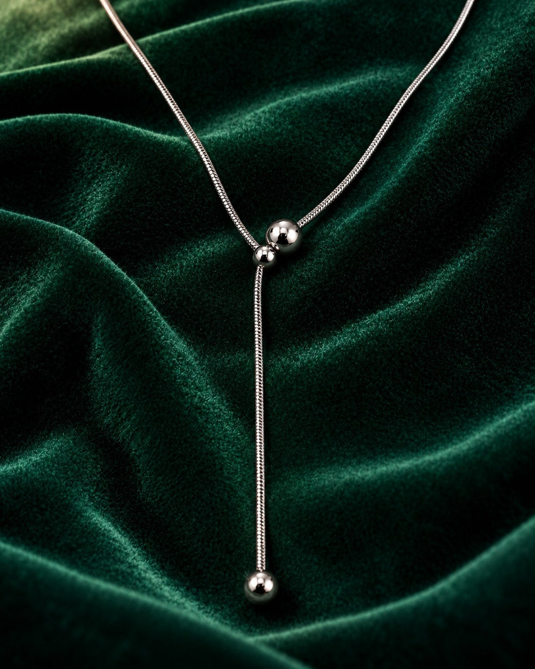 Elli Jewellery rhodium plated waterproof ball chain necklace on a luxurious dark green velvet background.