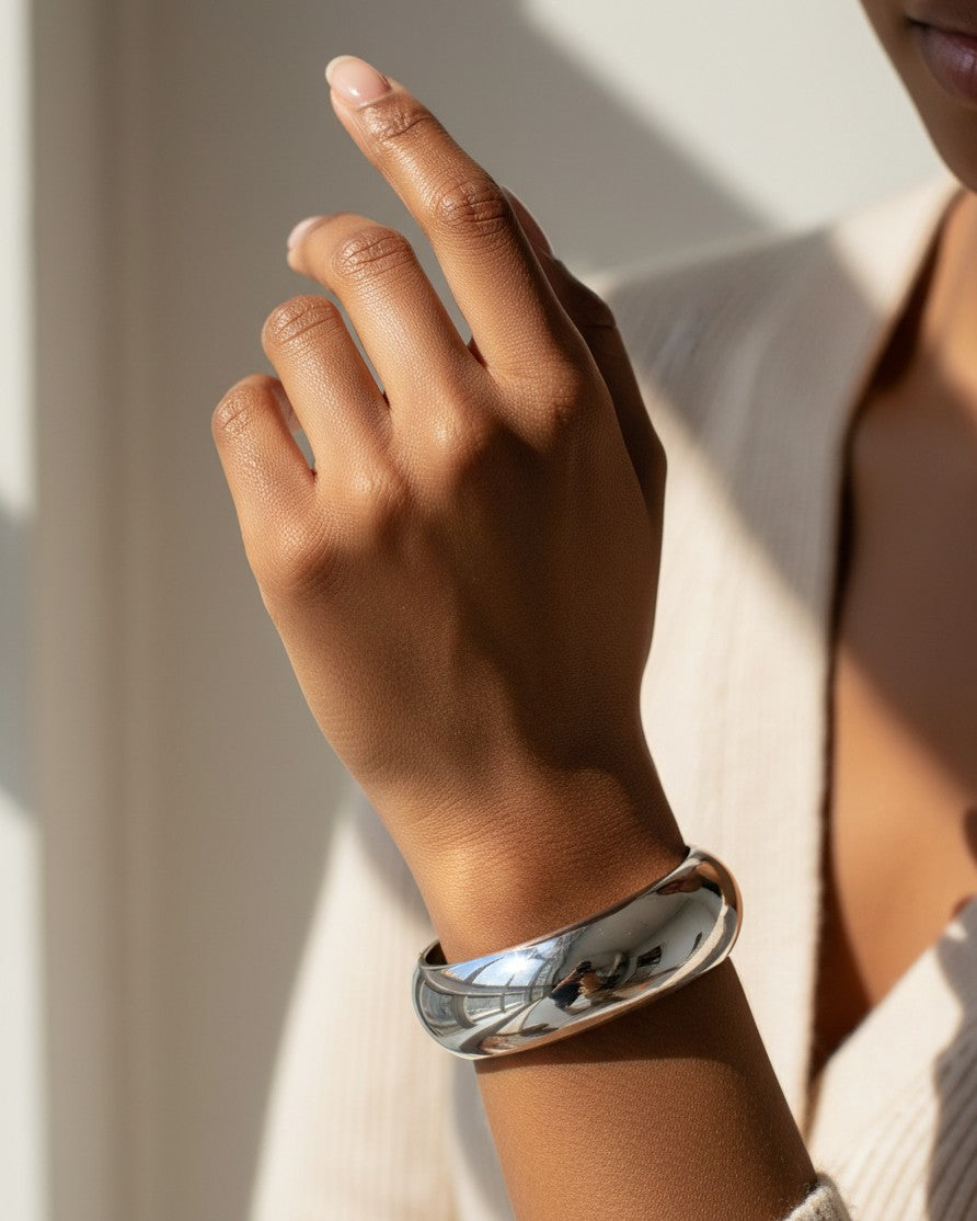 Elli Jewellery rhodium plated polished sleek bangle bracelet worn on a model's wrist in natural sunlight