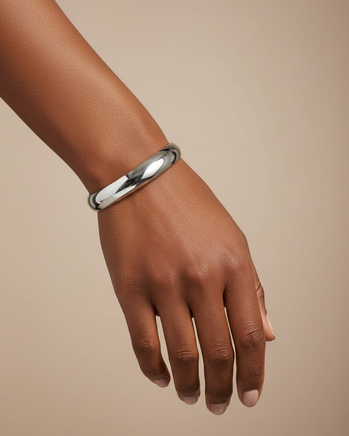 Elli Jewellery rhodium plated polished slim 1cm bangle bracelet worn on a model's wrist against a neutral background.