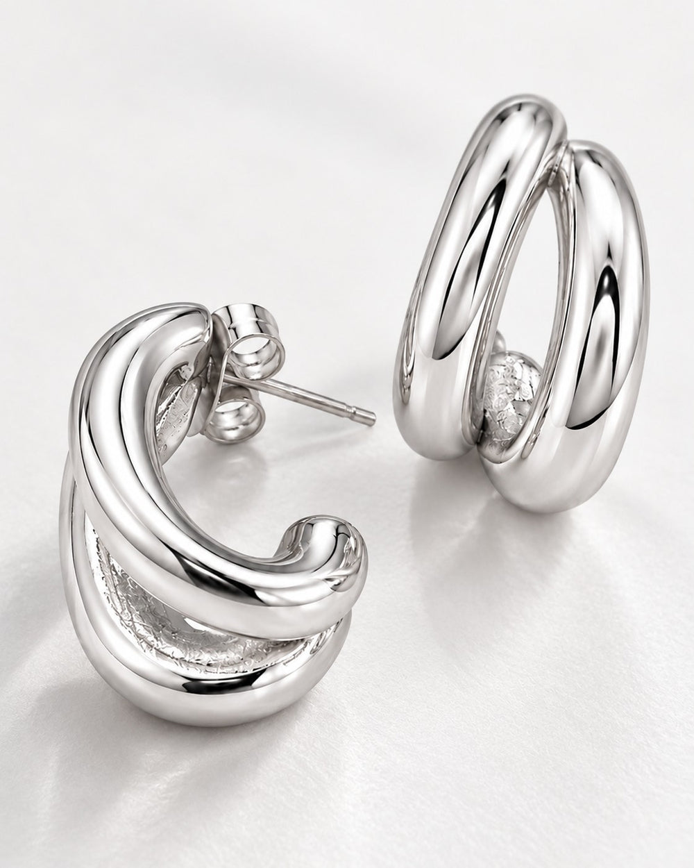 Elli Jewellery rhodium plated hollow C-shaped hoop earrings with a polished silver-tone finish on a white background.