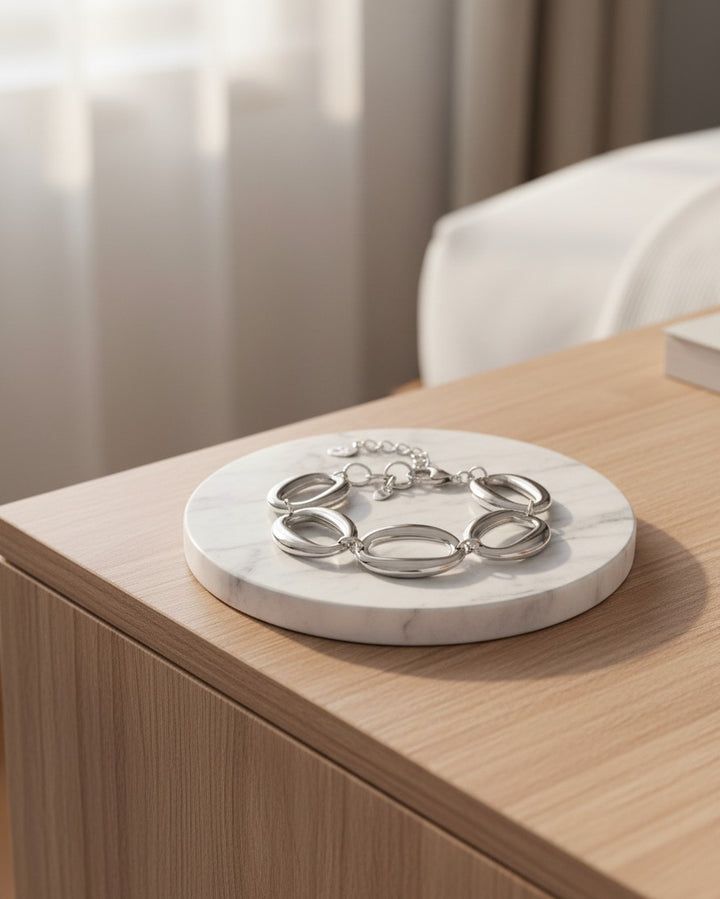 Elli Jewellery rhodium plated chunky chain link bracelet resting on a white marble circular tray on a wooden table.