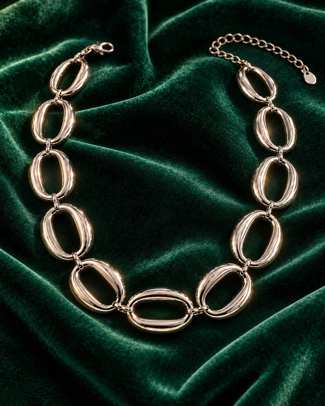 Elli Jewellery rhodium plated chunky statement chain necklace with oval links on a dark green velvet background.