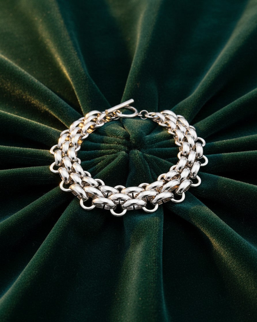 Elli Jewellery rhodium plated chunky toggle chain bracelet resting on a dark green velvet background