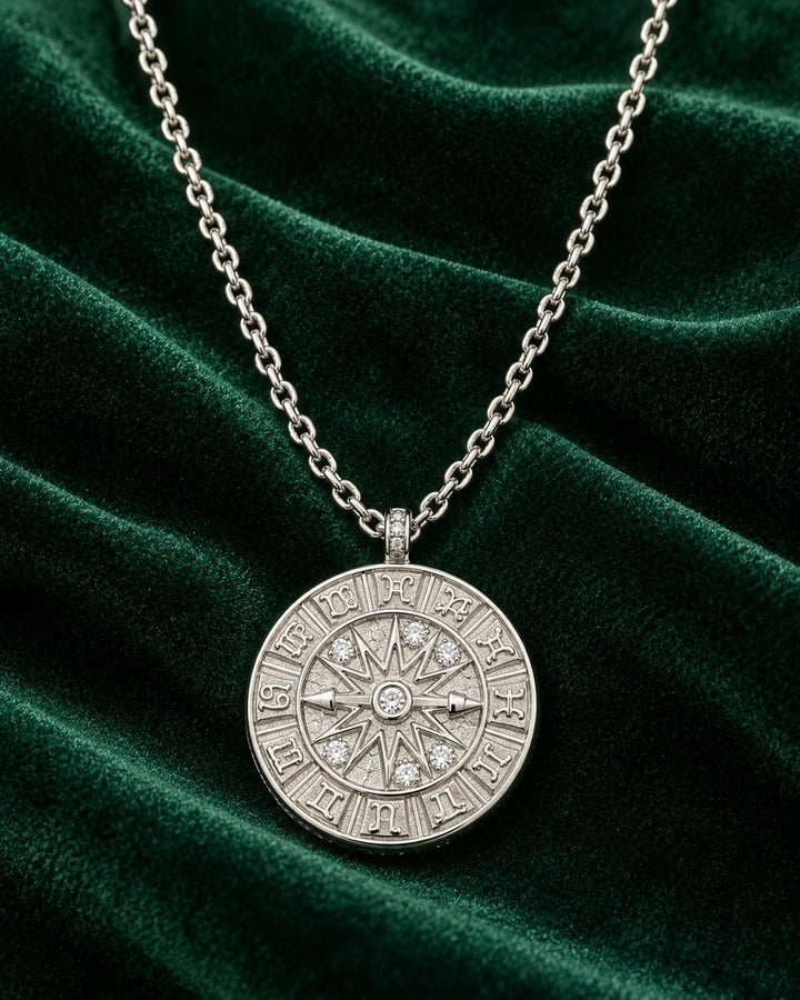 Elli Jewellery rhodium plated compass coin pendant necklace with crystal accents on a dark green velvet background