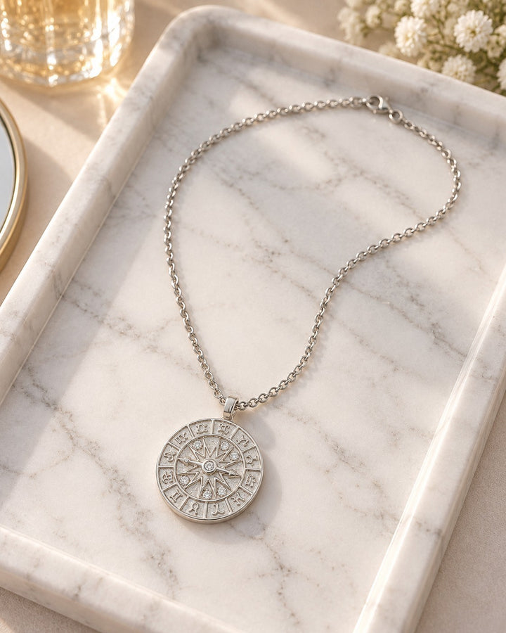 Elli Jewellery rhodium plated compass coin pendant necklace with intricate detailing on a white marble tray.