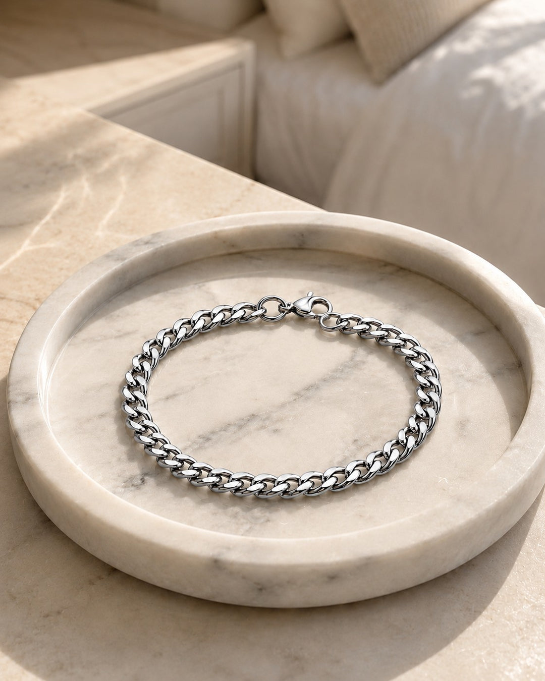 Elli Jewellery rhodium plated silver curb chain bracelet resting on a circular marble tray in soft sunlight.