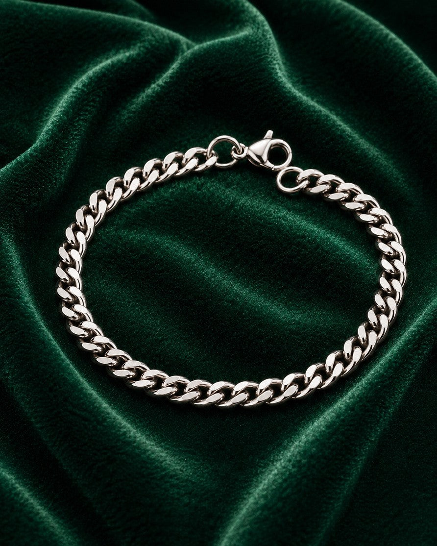 Elli Jewellery rhodium plated curb chain bracelet with a lobster clasp on a dark green velvet background.