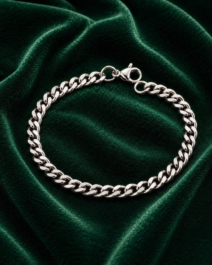 Elli Jewellery rhodium plated curb chain bracelet with a lobster clasp on a dark green velvet background.