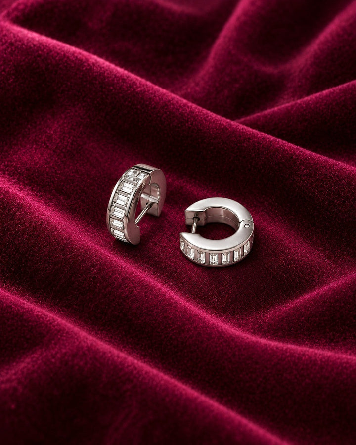 Elli Jewellery rhodium plated hoop earrings featuring baguette cut diamante stones on a deep red velvet background.