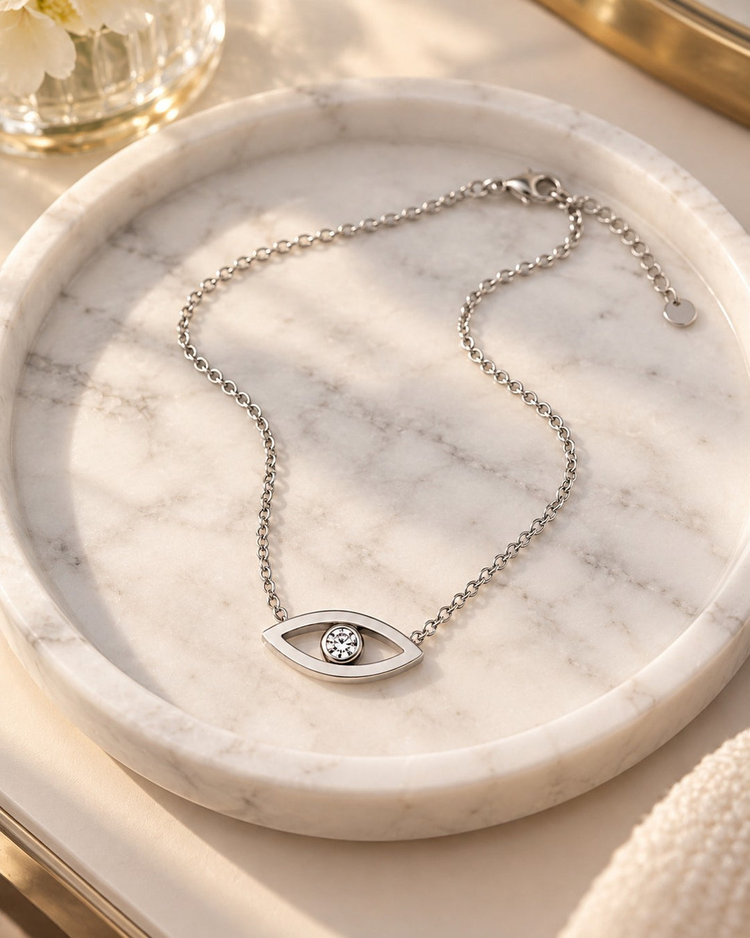 Elli Jewellery rhodium plated evil eye pendant necklace with a central cubic zirconia stone on a marble tray.