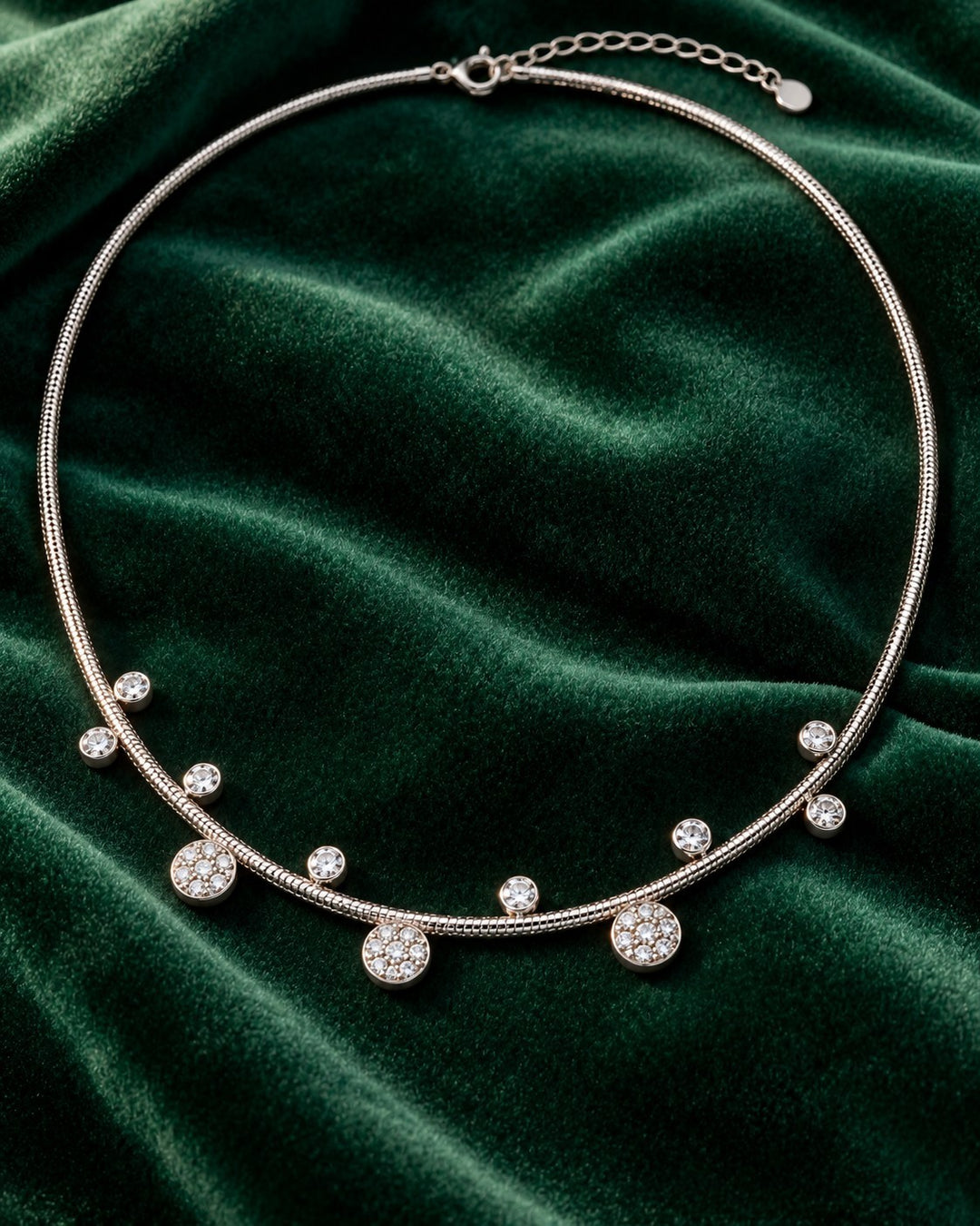 Elli Jewellery rhodium plated necklace featuring delicate circular floral charms with crystals on a green velvet base.