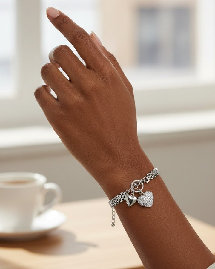 Elli Jewellery rhodium plated waterproof chain bracelet with two heart charms worn on a woman's wrist.