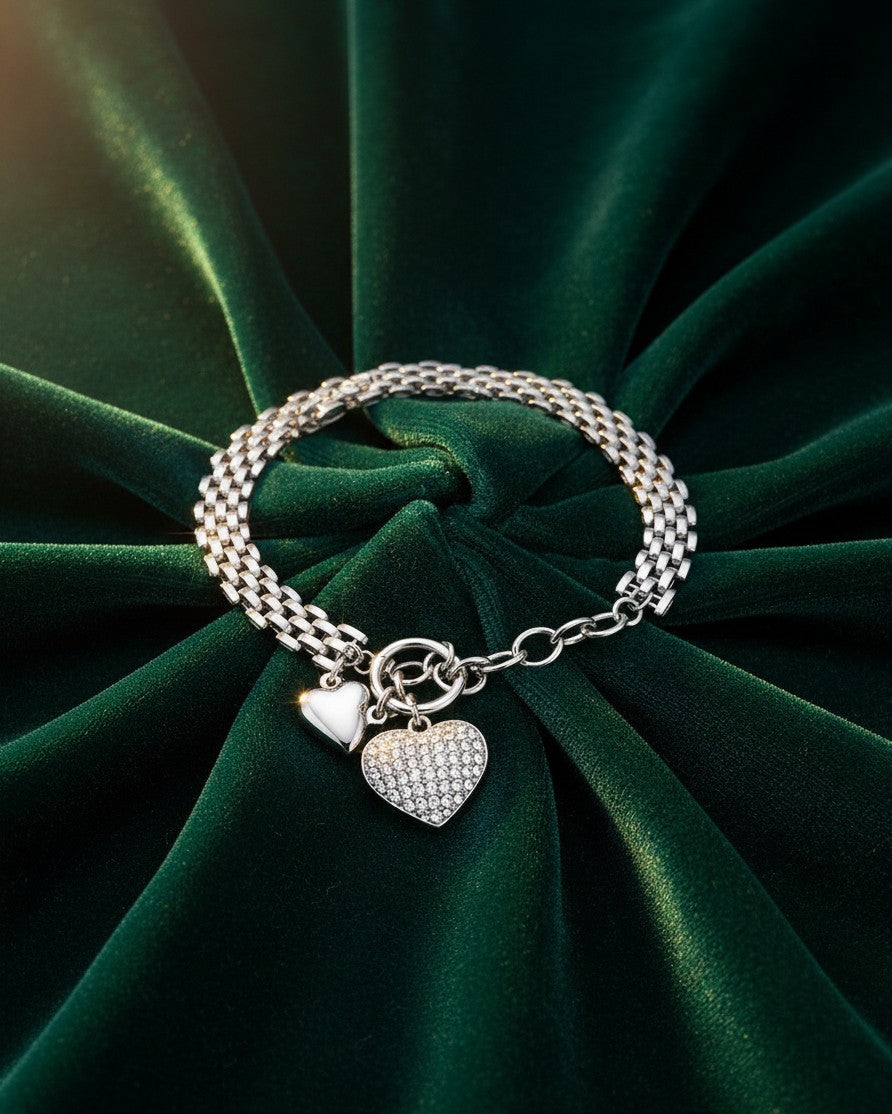 Elli Jewellery rhodium plated chain bracelet with two heart charms on a dark green velvet background