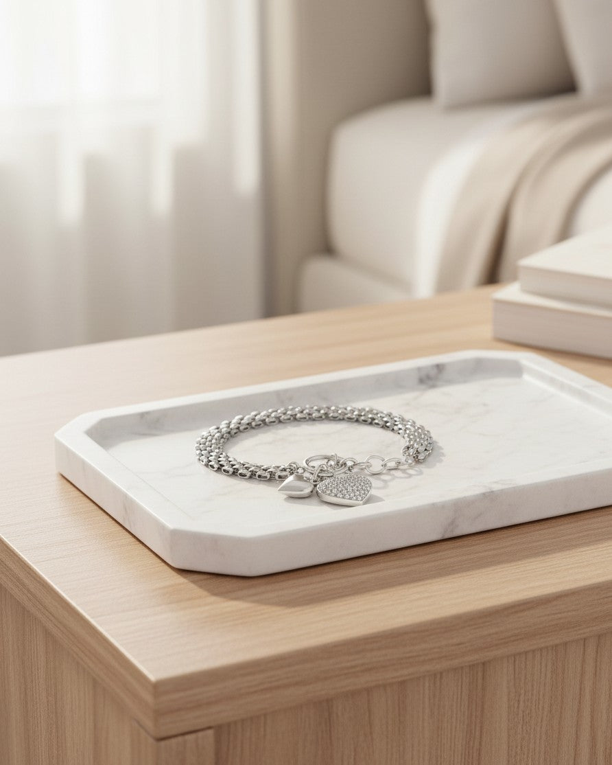 Elli Jewellery rhodium plated waterproof chain bracelet with a sparkling heart charm on a marble tray.